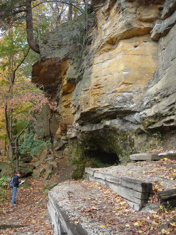 student at base of towering sandstone cliff