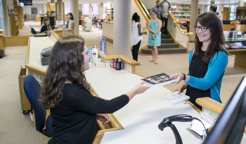 A library student worker assisting another student at the Circulation Desk