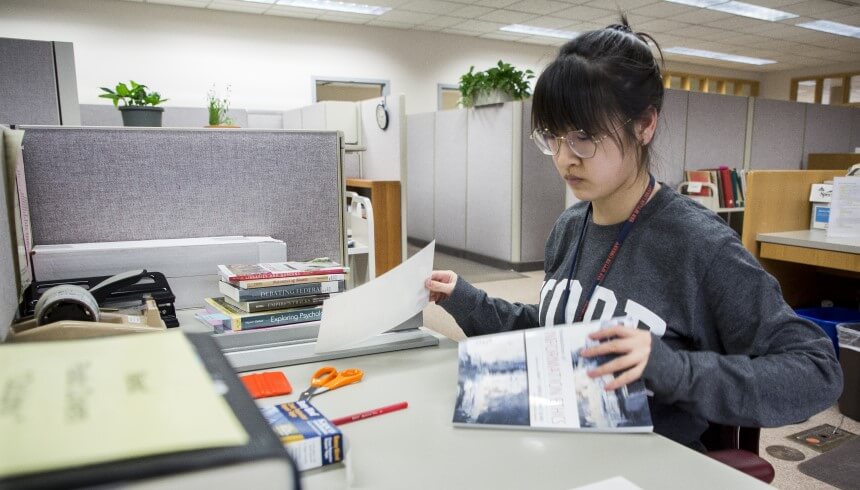 A library student worker processing an item in the Technical Services department