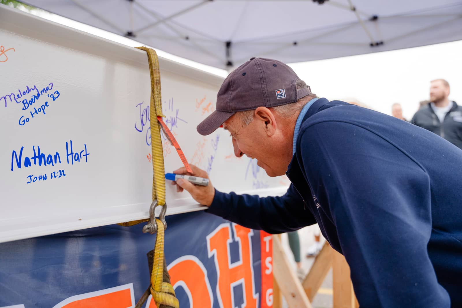 A male member of the Hope College community signing the beam for the Economics & Business building Topping Off ceremony