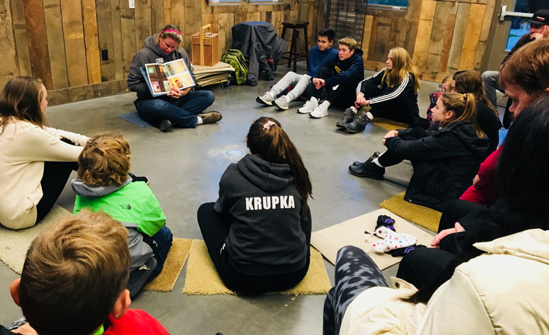 A woman reading a picture book to a group of children