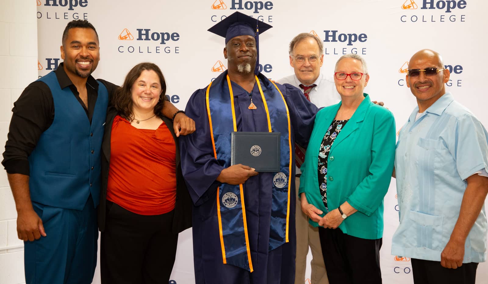 Hope-Western Prison Education Program graduates and staff in front of a Hope College banner