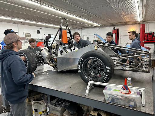 Students working on race car in shop.