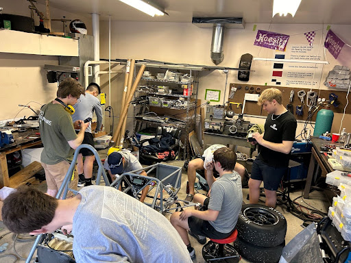 Students working on formula car in shop.